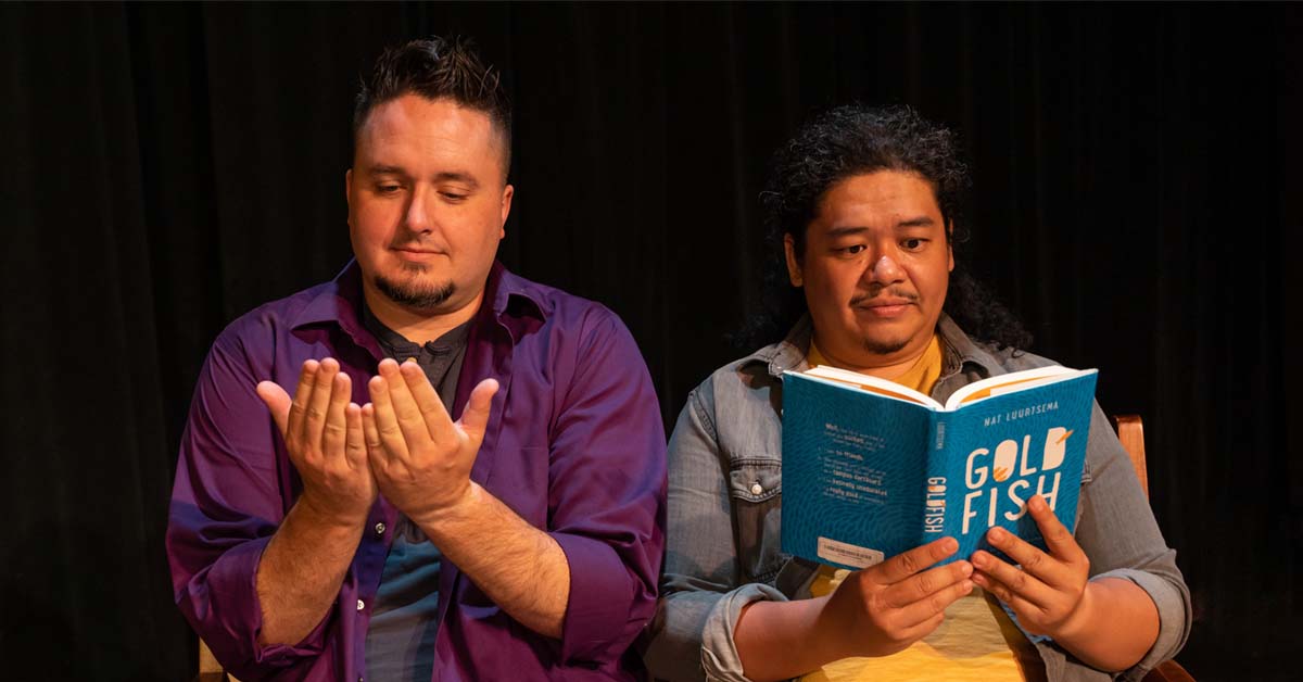 [image: Dane Lentz making the sign for "book" as Tasi Alabastro reads a book]