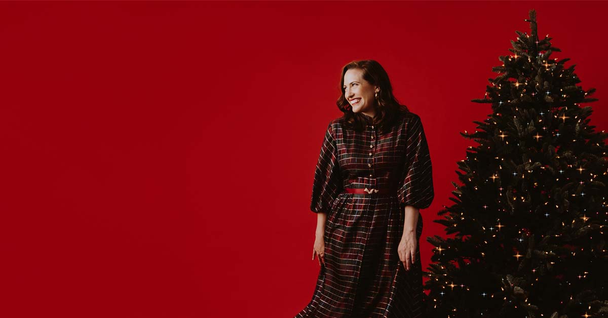 [image: Singer Ren Geisick with a Christmas tree against a red background]