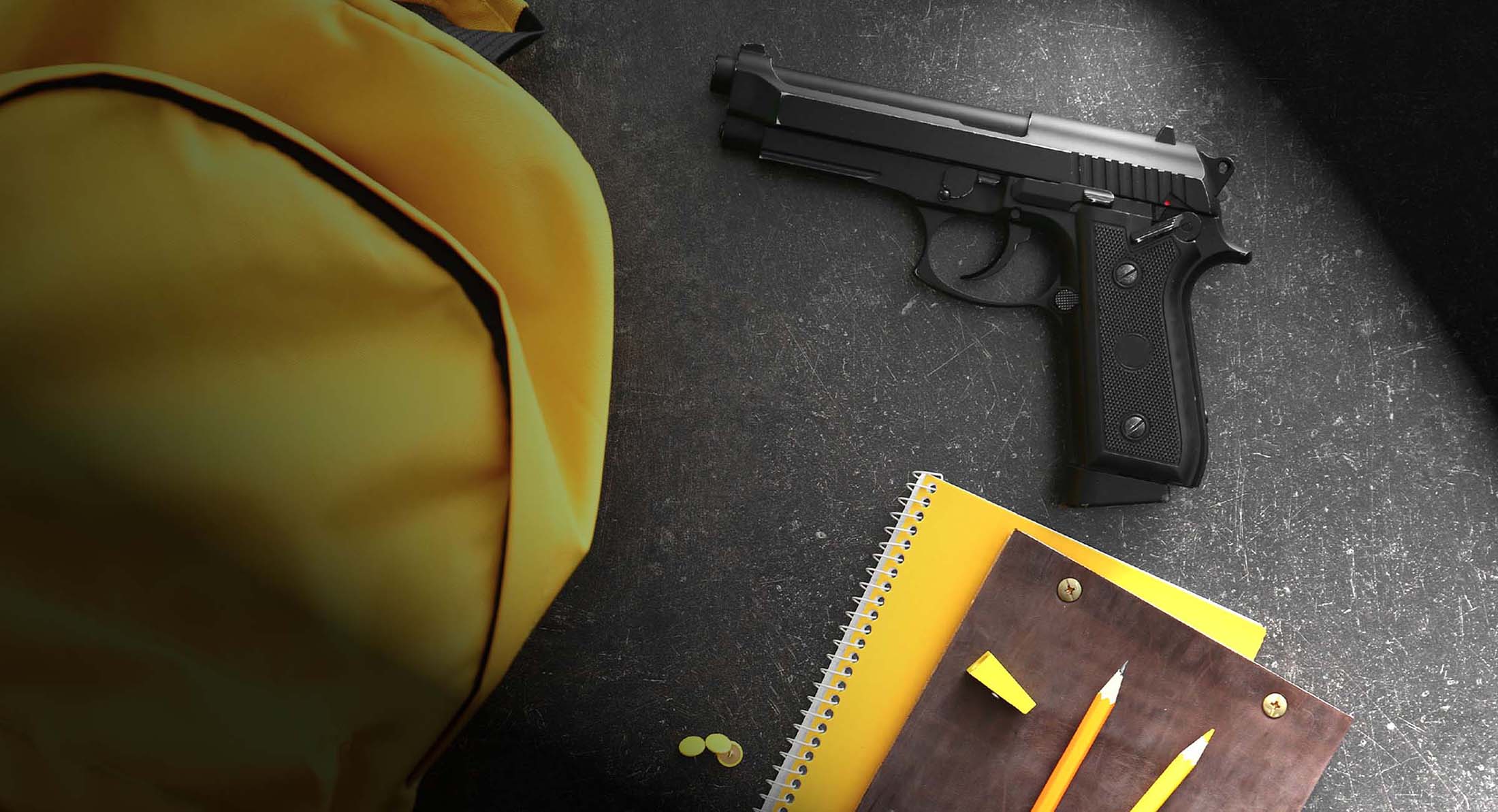 [image: Yellow backpack and school supplies, including a gun, under dramatic lighting]