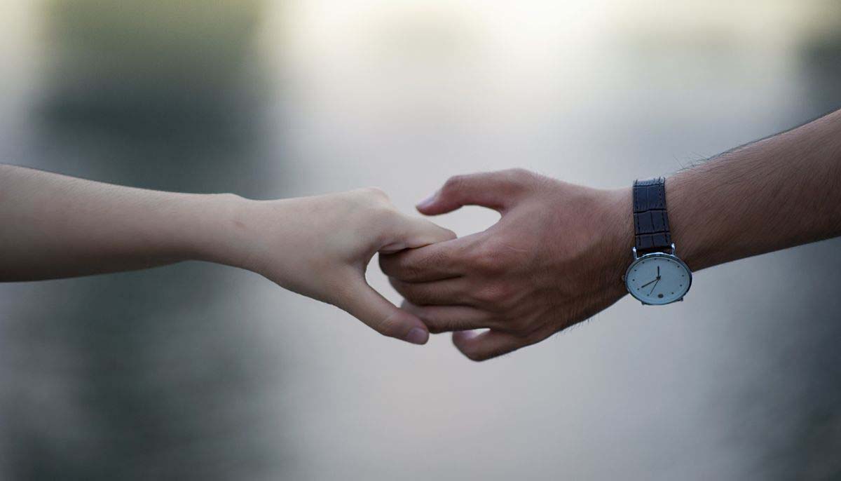 [image: White hand holding Black hand against a soft, blurry, pale background]