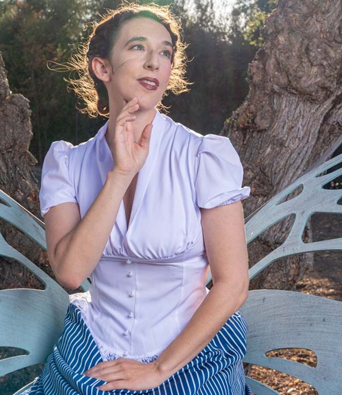 [image: Female actor smiling wistfully, hand at her chin, with the sun haloed behind her]