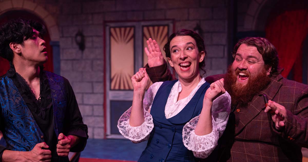 [image: Two actors, male and female, beam with huge smiles while wearing period Victorian costumes. Another actor playing Dracula looks on, a little confused]